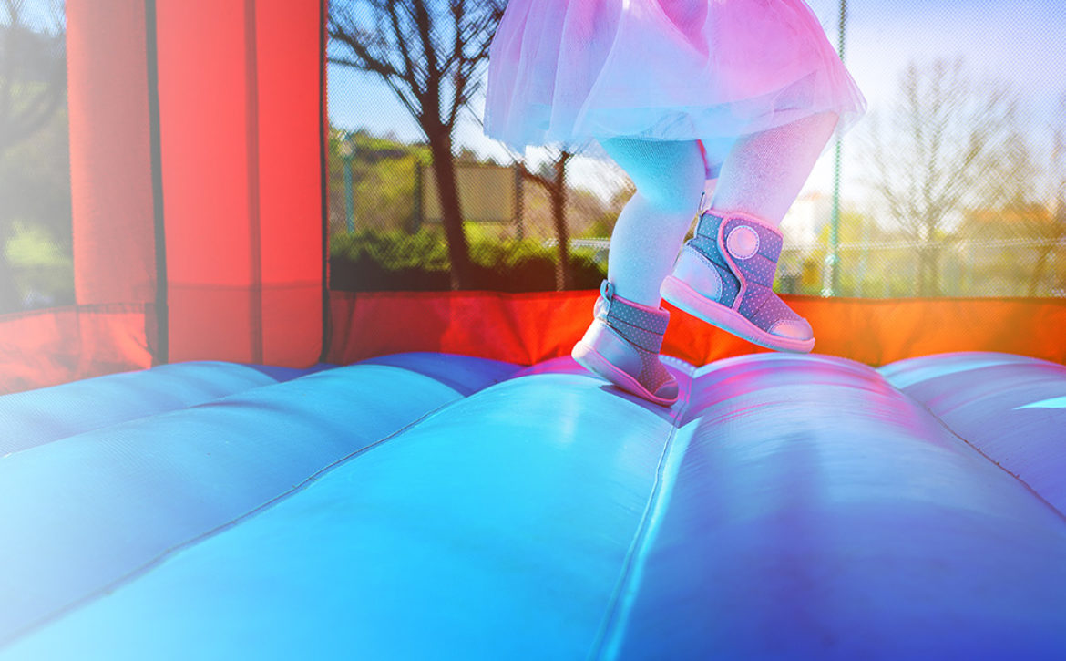 Happy child having fun on inflatable castle, slide, trampoline.